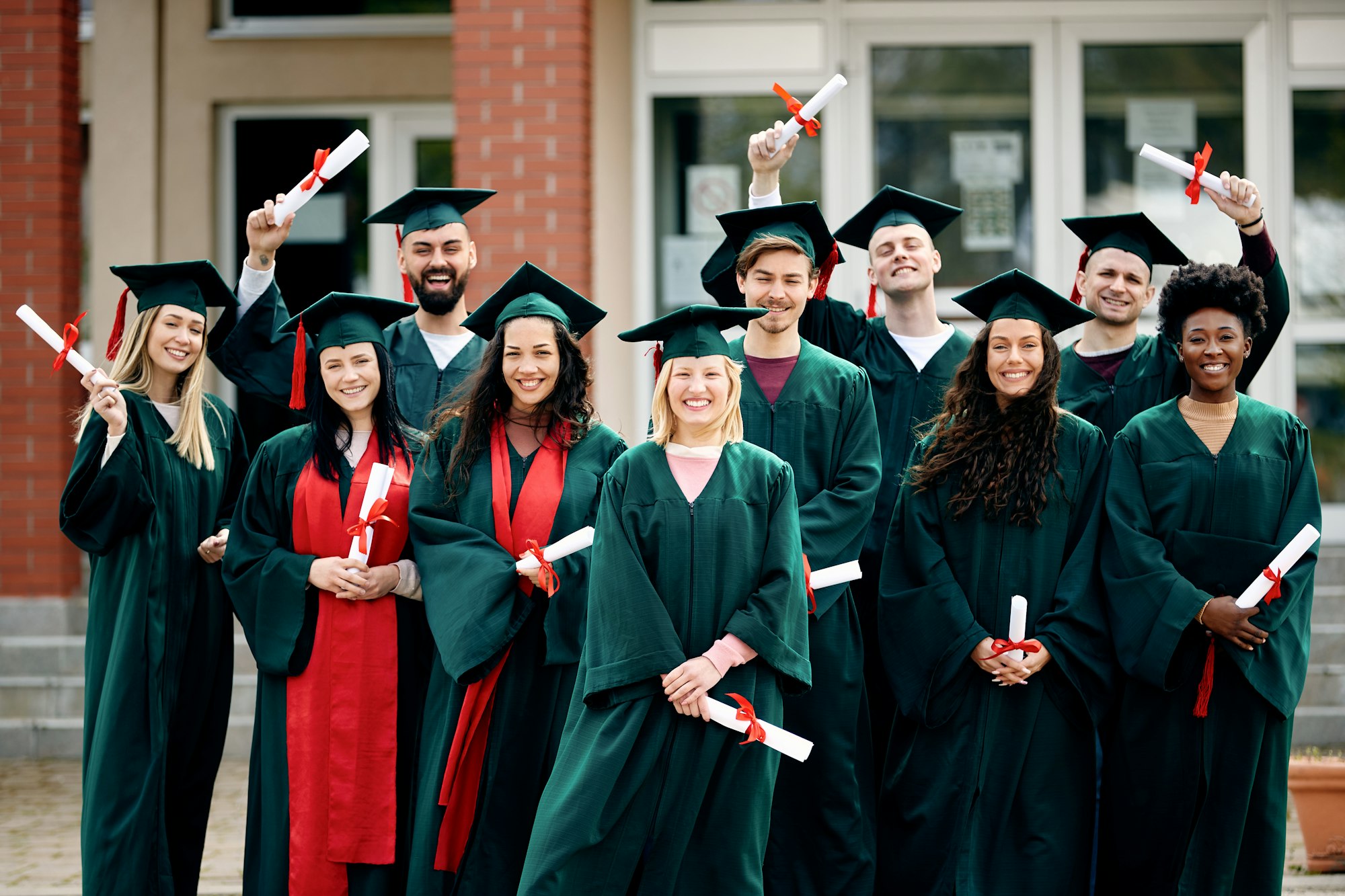 Group of multi-ethnic college friends celebrating their graduation and looking at camera.