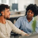 Portrait of an interracial call center manager discussing with colleague.