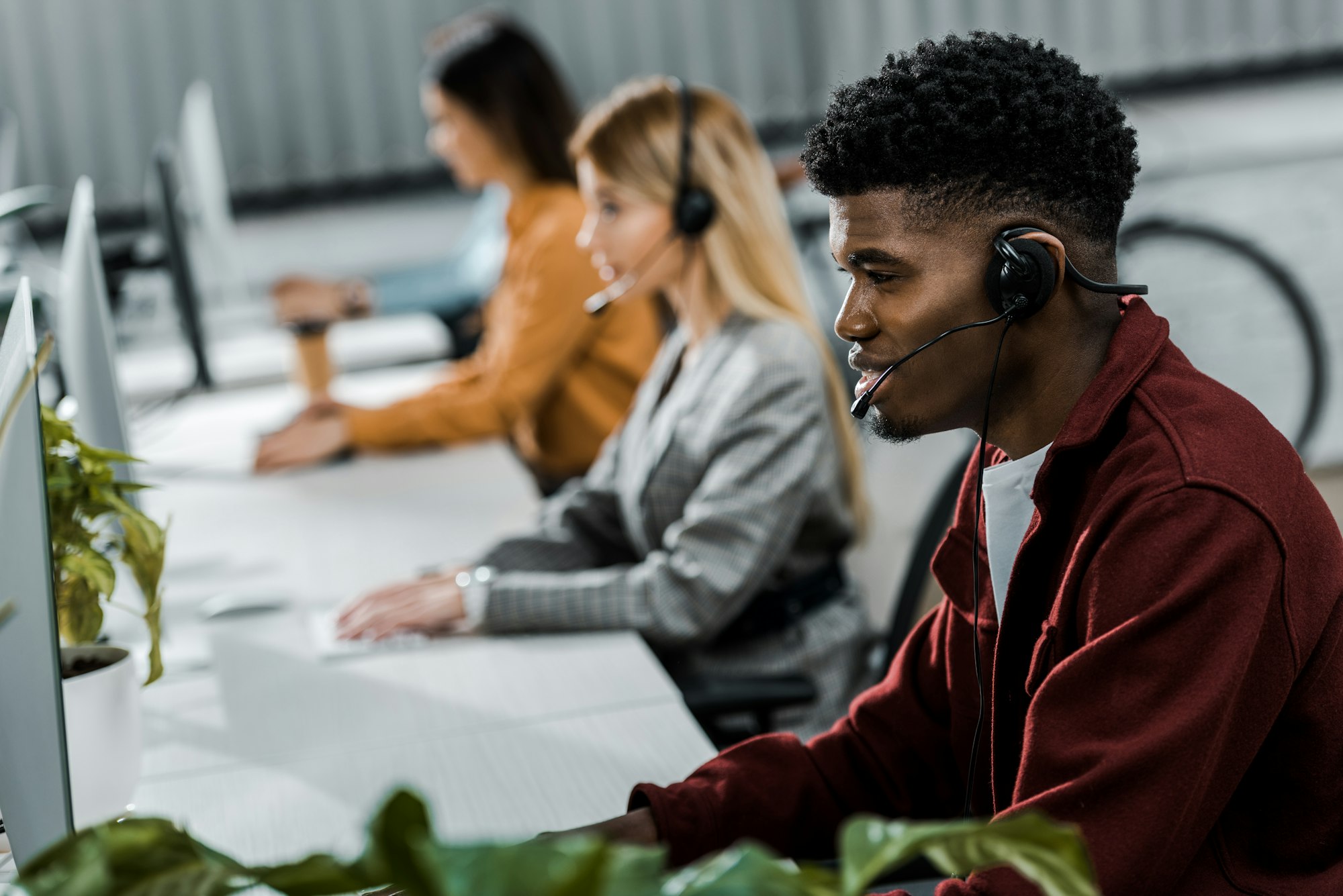 multicultural call center operators with headsets at workpalce in office